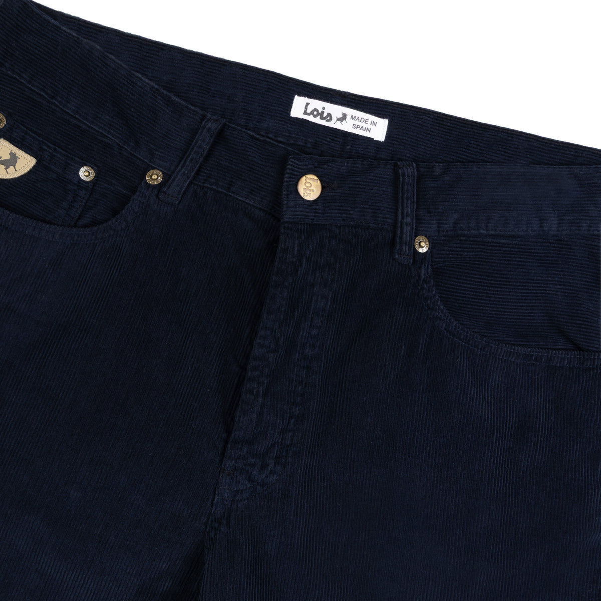 Close-up of dark navy corduroy jeans showing the waistband, button, rivets, and a white Lois brand label and triangular suede coin pocket branding. Shot on a white background