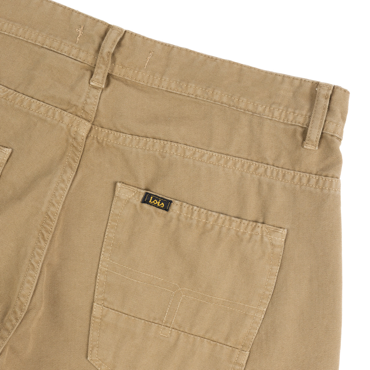 Close-up of the back waistband and right rear pocket of fall leaf coloured canvas jeans, showing a small black and yellow Lois brand tag on the pocket.