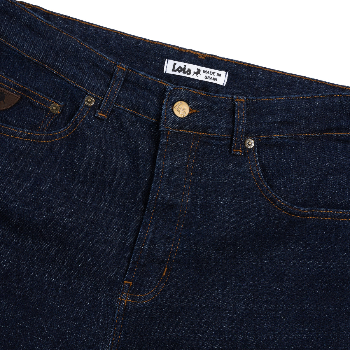 Close-up of dark blue denim jeans with a visible brand label on a white background