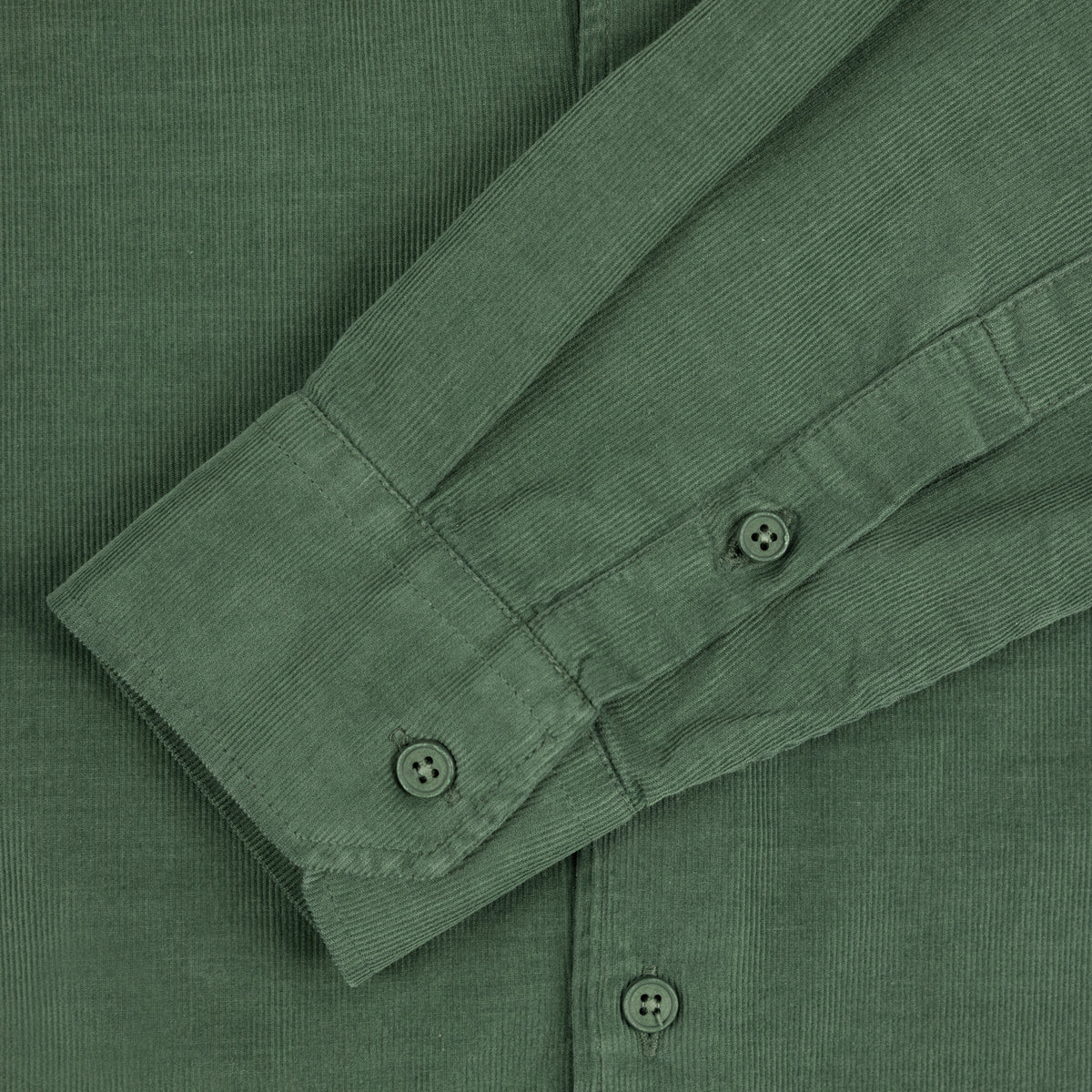 Close-up of a dried herb coloured corduroy button-down shirt showing the fabric texture and cuff detail.