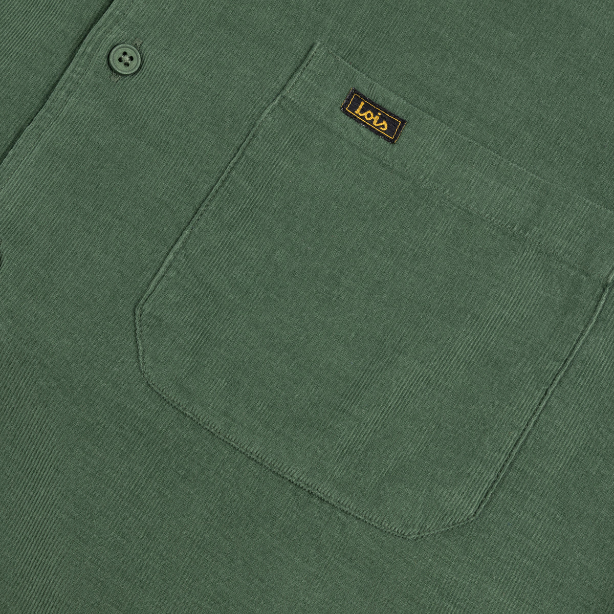 Close-up of a dried herb coloured  corduroy shirt pocket with a small brown brand label reading Lotus.
