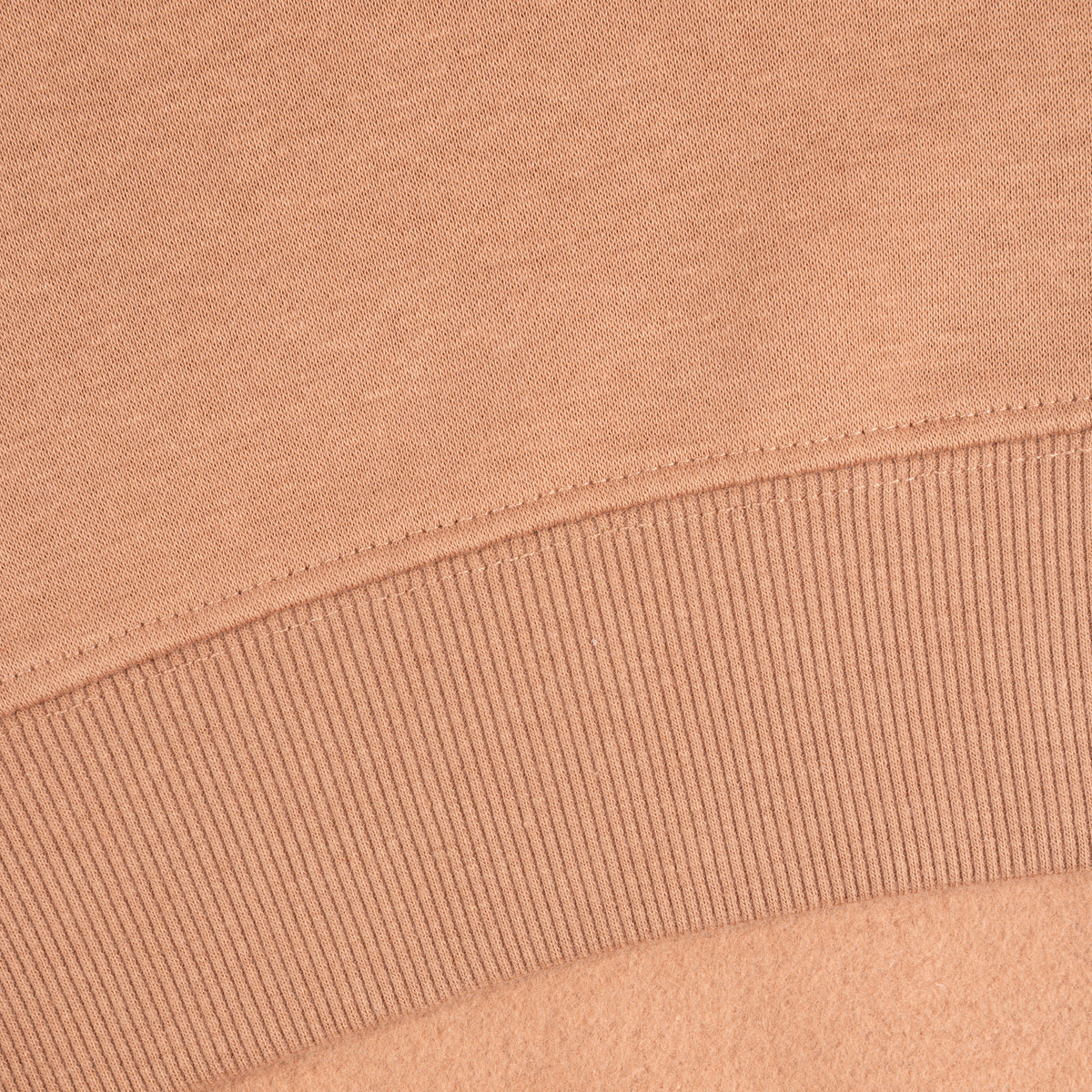 Close-up of a mocca brown-coloured knit fabric with a ribbed cuff and fine stitching.