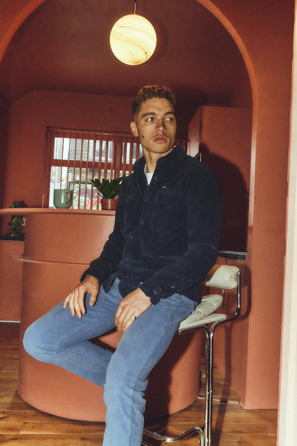 A dark navy blue corduroy button-up shirt jacket with two chest flap pockets, displayed flat against a solid white background.